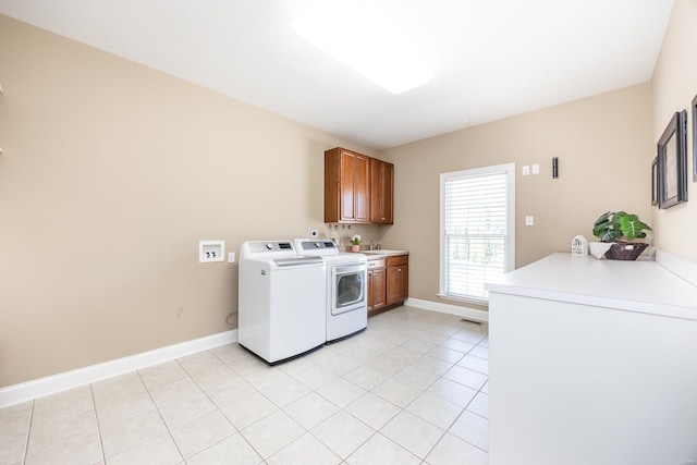 clothes washing area with light tile patterned floors, baseboards, cabinet space, a sink, and independent washer and dryer