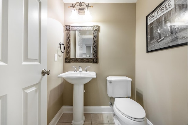 half bathroom with tile patterned floors, toilet, baseboards, and a sink