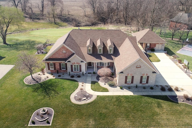 view of front facade with concrete driveway, a front yard, stone siding, and roof with shingles