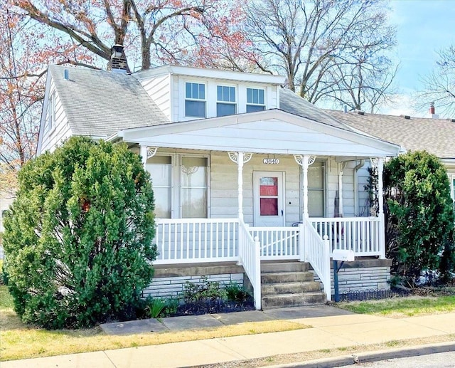 bungalow-style house with a porch, a shingled roof, and a chimney