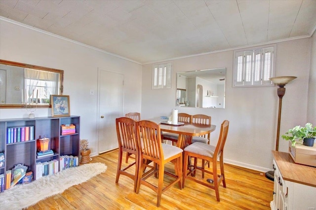 dining space featuring light wood-type flooring, baseboards, and ornamental molding