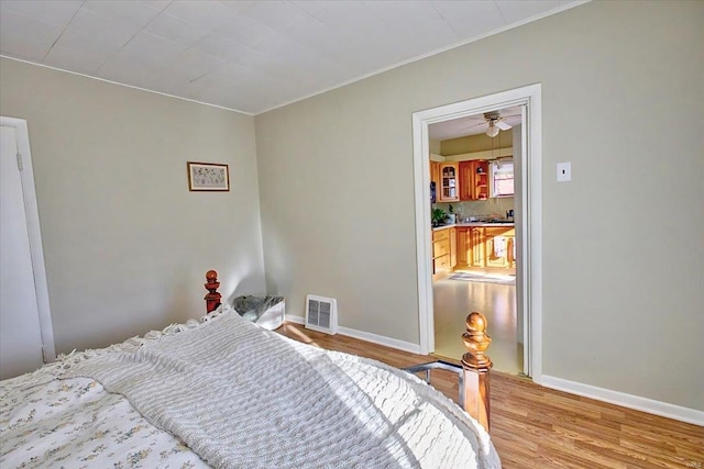 bedroom featuring light wood-style floors, visible vents, and baseboards