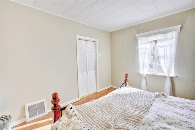 bedroom with ornamental molding, wood finished floors, visible vents, and baseboards