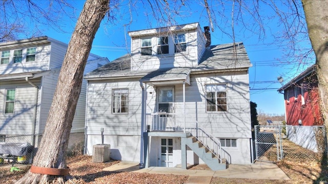 view of front of house with a chimney, cooling unit, fence, and a gate