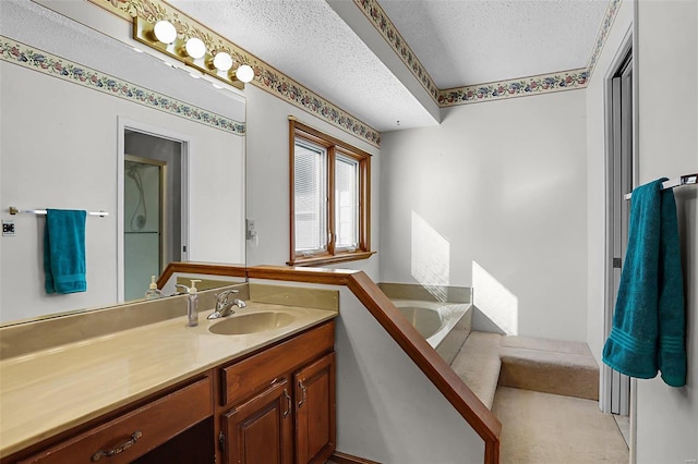 bathroom featuring a bath, a textured ceiling, and vanity