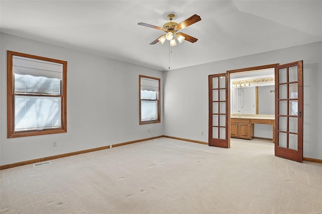 empty room featuring french doors, light colored carpet, ceiling fan, and baseboards