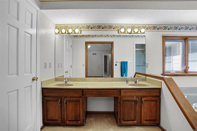 full bath with a sink, a textured ceiling, and double vanity