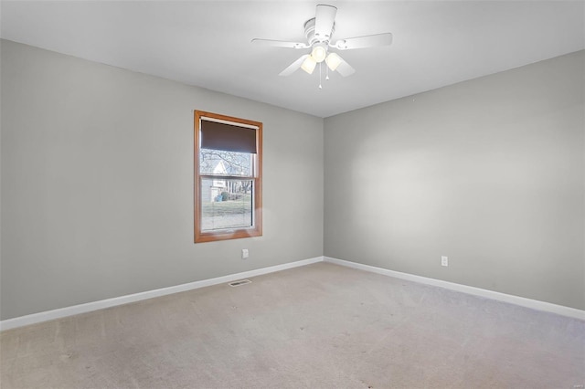 carpeted empty room featuring a ceiling fan, visible vents, and baseboards