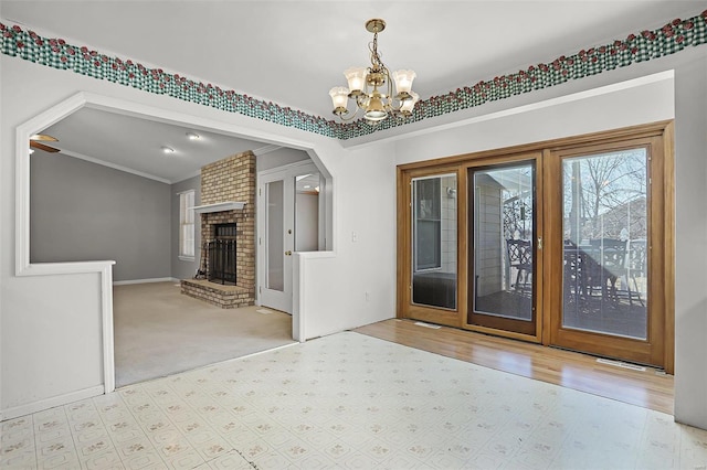 carpeted foyer featuring a chandelier, ornamental molding, a fireplace, and arched walkways