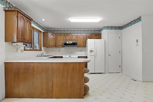 kitchen with light countertops, stainless steel microwave, stove, white fridge with ice dispenser, and a peninsula