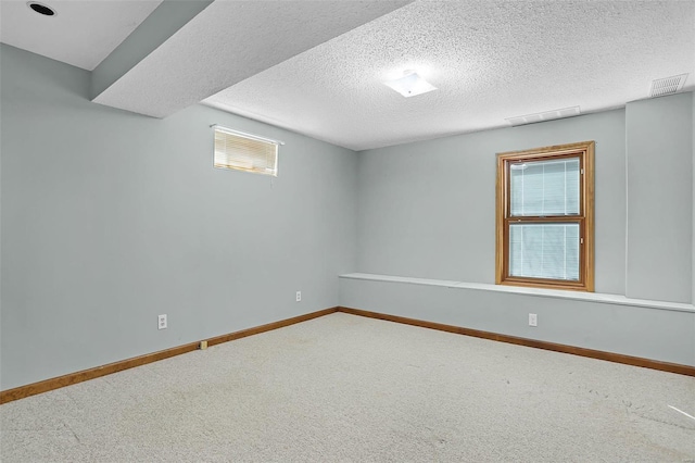 below grade area featuring a textured ceiling, carpet flooring, visible vents, and baseboards