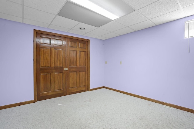 unfurnished bedroom featuring a paneled ceiling, carpet, and baseboards