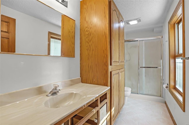 bathroom featuring toilet, a stall shower, visible vents, and a textured ceiling