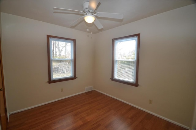 spare room featuring baseboards, visible vents, ceiling fan, and wood finished floors