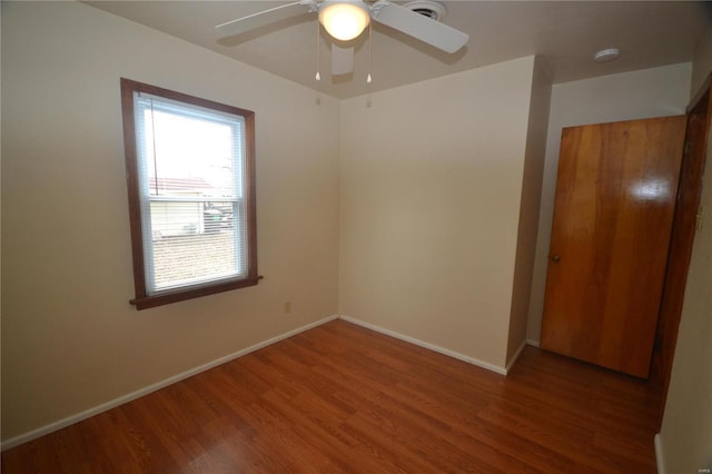 unfurnished room featuring ceiling fan, wood finished floors, and baseboards