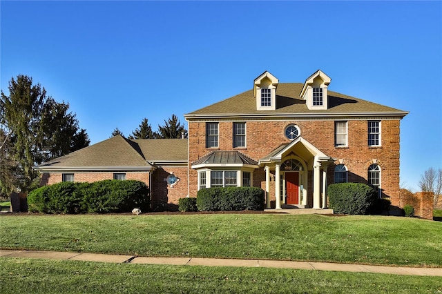 colonial-style house featuring brick siding and a front yard