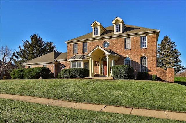 georgian-style home featuring a front yard and brick siding