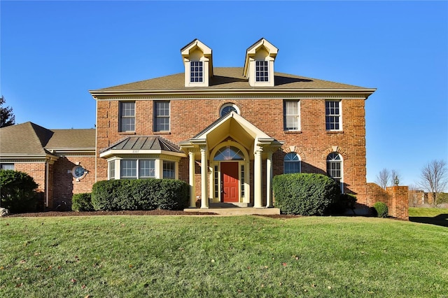 colonial home with brick siding and a front yard