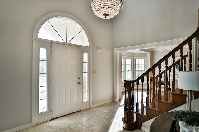 entryway featuring a towering ceiling, stairway, baseboards, and light tile patterned floors