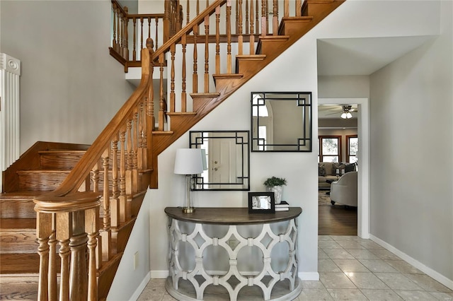 stairway featuring a ceiling fan, tile patterned flooring, and baseboards