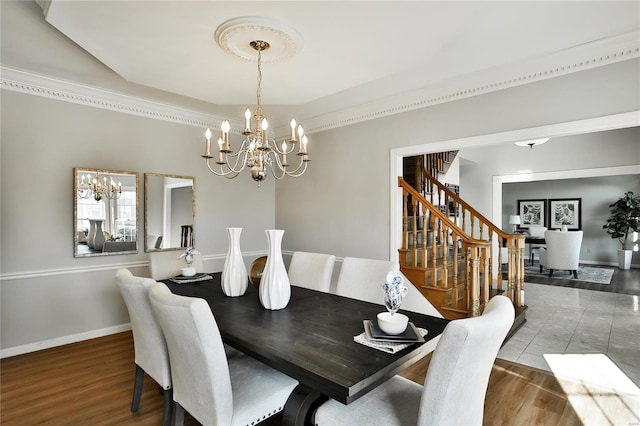 dining space featuring an inviting chandelier, stairs, baseboards, and wood finished floors