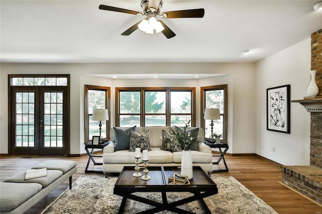 living area featuring baseboards, french doors, wood finished floors, and a healthy amount of sunlight