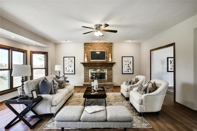 living room with a fireplace, baseboards, dark wood finished floors, and a ceiling fan