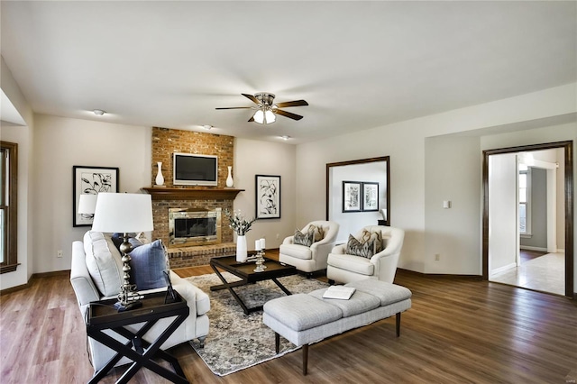 living room featuring ceiling fan, a fireplace, baseboards, and wood finished floors