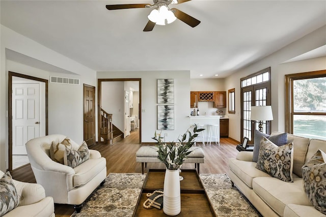 living area with light wood-style flooring, recessed lighting, visible vents, and stairway