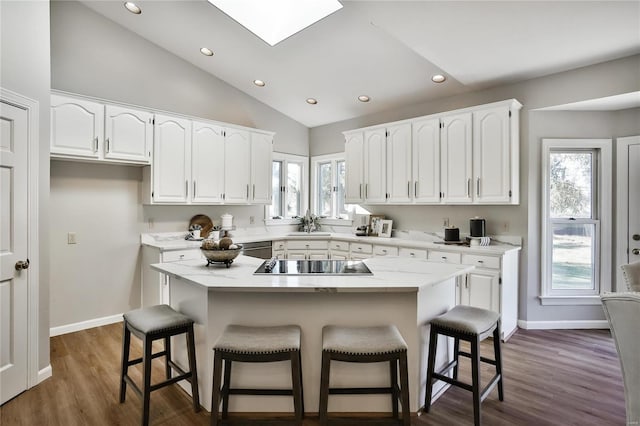 kitchen featuring vaulted ceiling with skylight, white cabinetry, and black electric cooktop