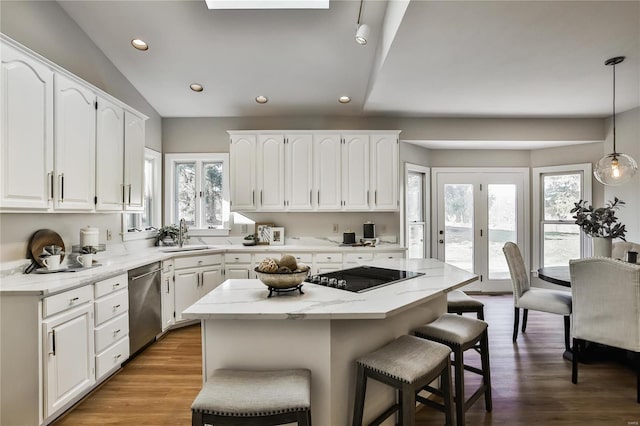 kitchen with a breakfast bar, black electric stovetop, stainless steel dishwasher, white cabinets, and a sink