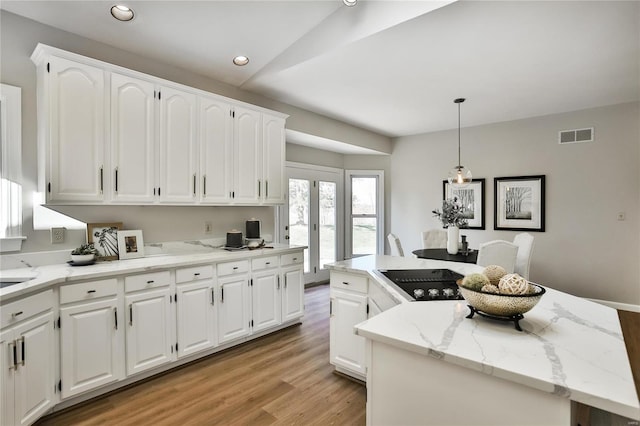 kitchen with recessed lighting, visible vents, light wood-style floors, white cabinets, and a kitchen island