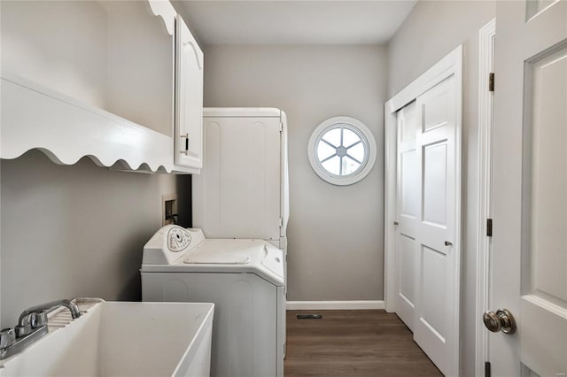 laundry area featuring cabinet space, baseboards, dark wood-style floors, washer / clothes dryer, and a sink