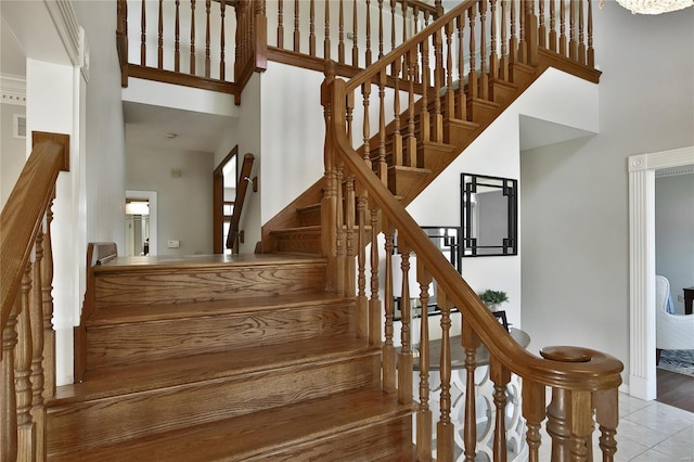 staircase with a high ceiling, visible vents, and tile patterned floors