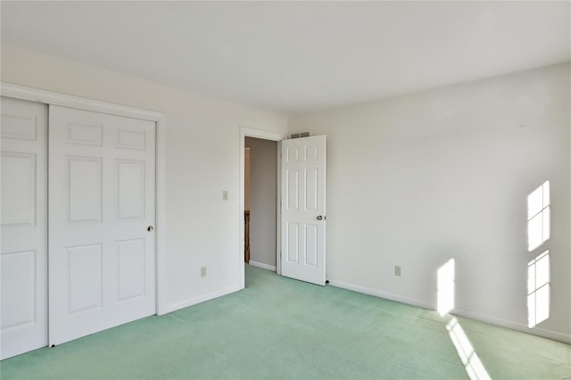 unfurnished bedroom featuring a closet, light colored carpet, visible vents, and baseboards