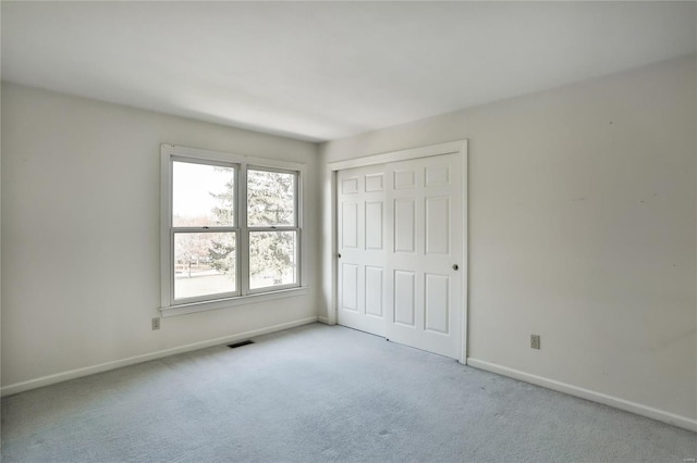 unfurnished bedroom with carpet floors, a closet, visible vents, and baseboards