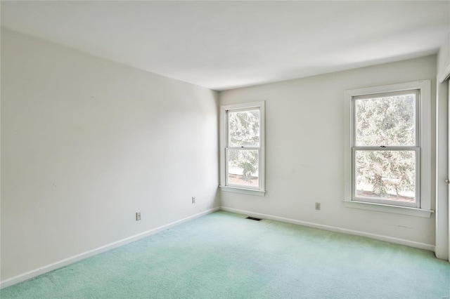 spare room with baseboards, visible vents, and light colored carpet