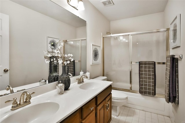 bathroom featuring toilet, double vanity, a sink, and visible vents