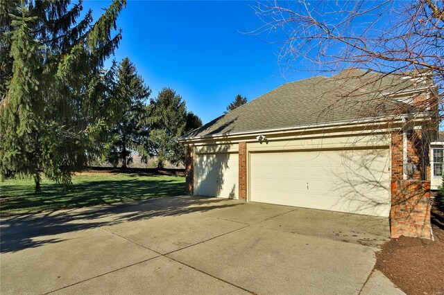 view of home's exterior with a garage, concrete driveway, brick siding, and roof with shingles