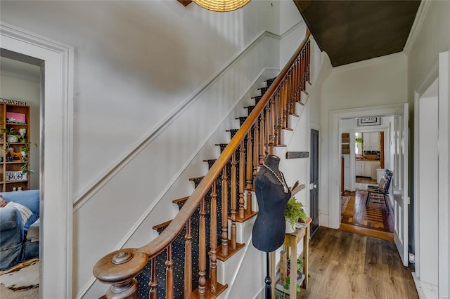 stairway with wood finished floors and ornamental molding