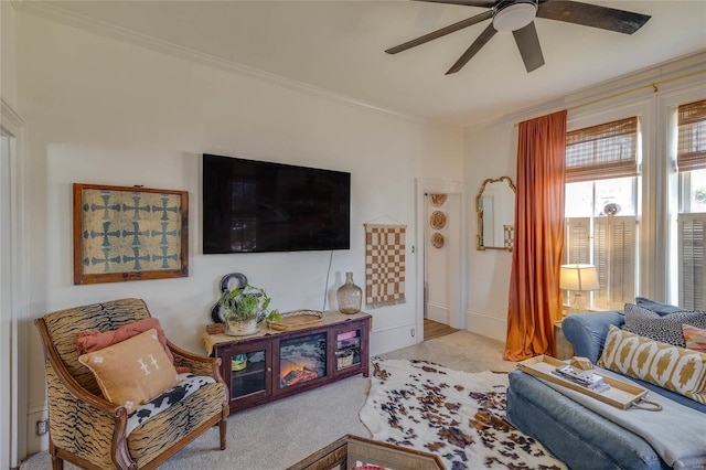 carpeted living room featuring ornamental molding and a ceiling fan