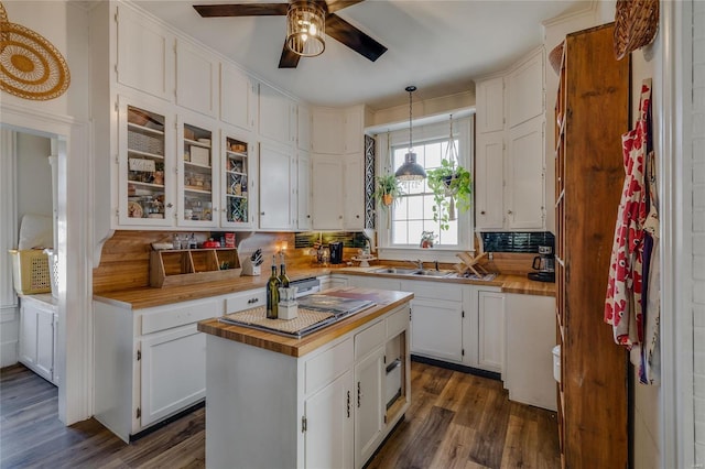 kitchen with glass insert cabinets, butcher block countertops, dark wood-style floors, white cabinets, and a sink