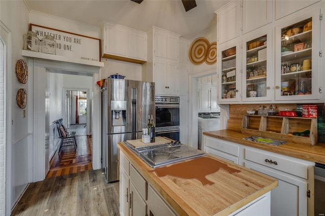 kitchen featuring white cabinetry, ornamental molding, butcher block countertops, and stainless steel appliances