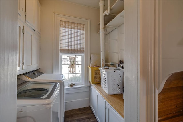 clothes washing area with dark wood-style floors, washing machine and dryer, and cabinet space