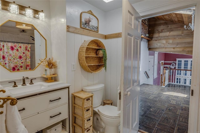 full bath featuring wooden walls, toilet, and vanity