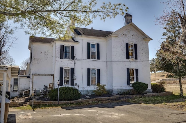 view of front facade with brick siding and a chimney