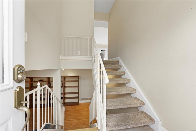 staircase with visible vents, wood finished floors, and baseboards