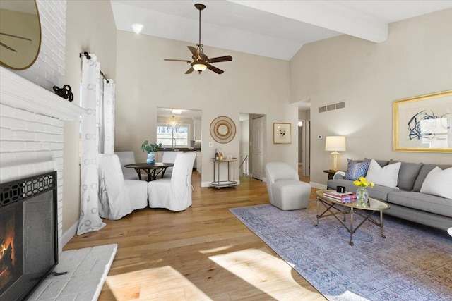 living area featuring visible vents, ceiling fan, a fireplace, wood finished floors, and high vaulted ceiling