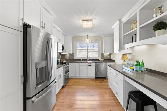 kitchen featuring dark countertops, white cabinetry, stainless steel appliances, and a sink