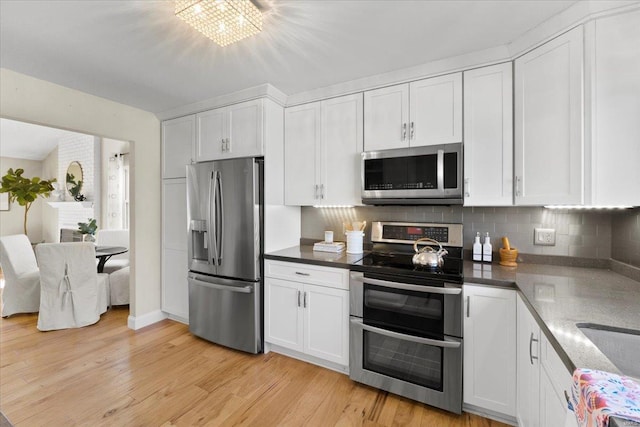 kitchen with white cabinetry, decorative backsplash, light wood-type flooring, and appliances with stainless steel finishes